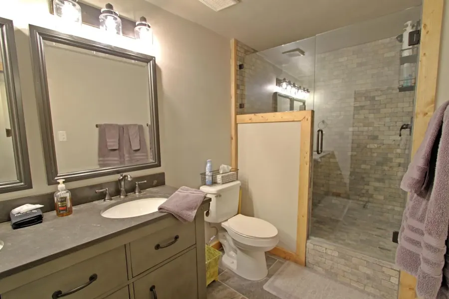 The bottom level bathroom has a tile shower with a low step.